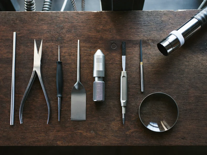 Illustration d'outils de précision disposés sur un établi en bois patiné.